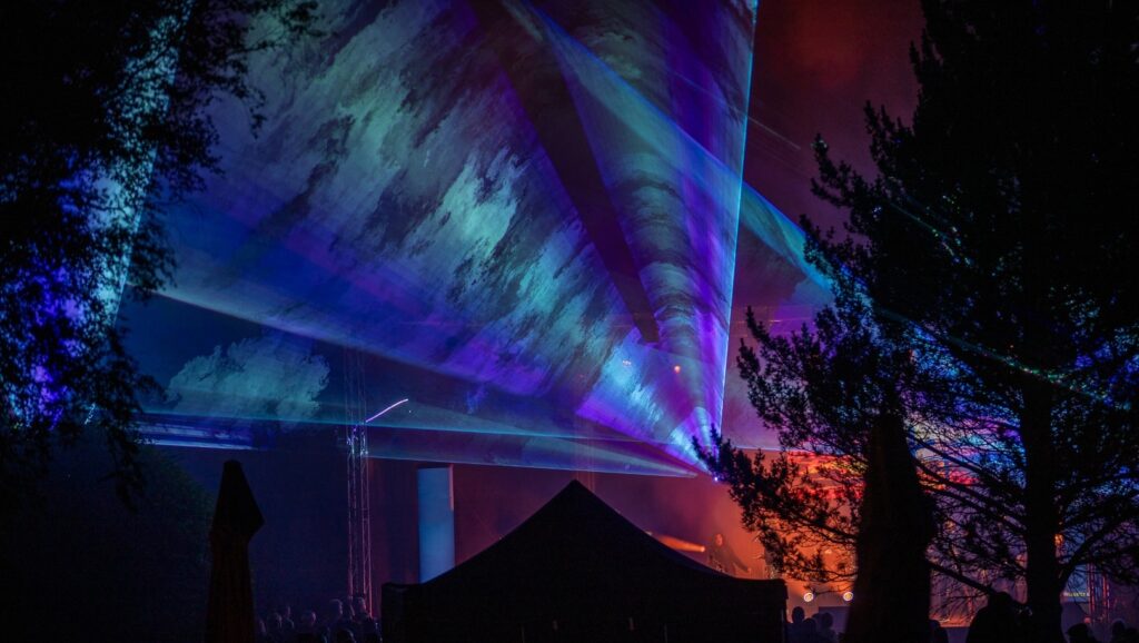 Nächtliche Outdoor-Lasershow mit blauen und violetten Lichtstrahlen